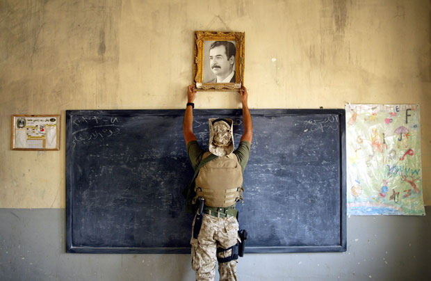 Chris Hondros – marine retirando la foto de Sadam Hussein en una escuela