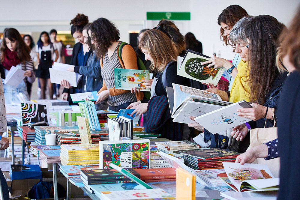 El FLIC Festival 2020 homenajea a los personajes singulares de la literatura ilustrada. Personas, en la feria, consultando libros.